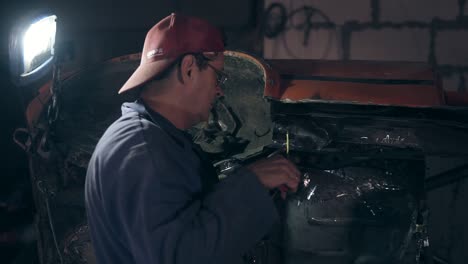 Workman-in-red-cap-and-glasses-equiped-with-protective-gloves-takes-measuremeants-from-some-unrecogniyable-car-like-construction.