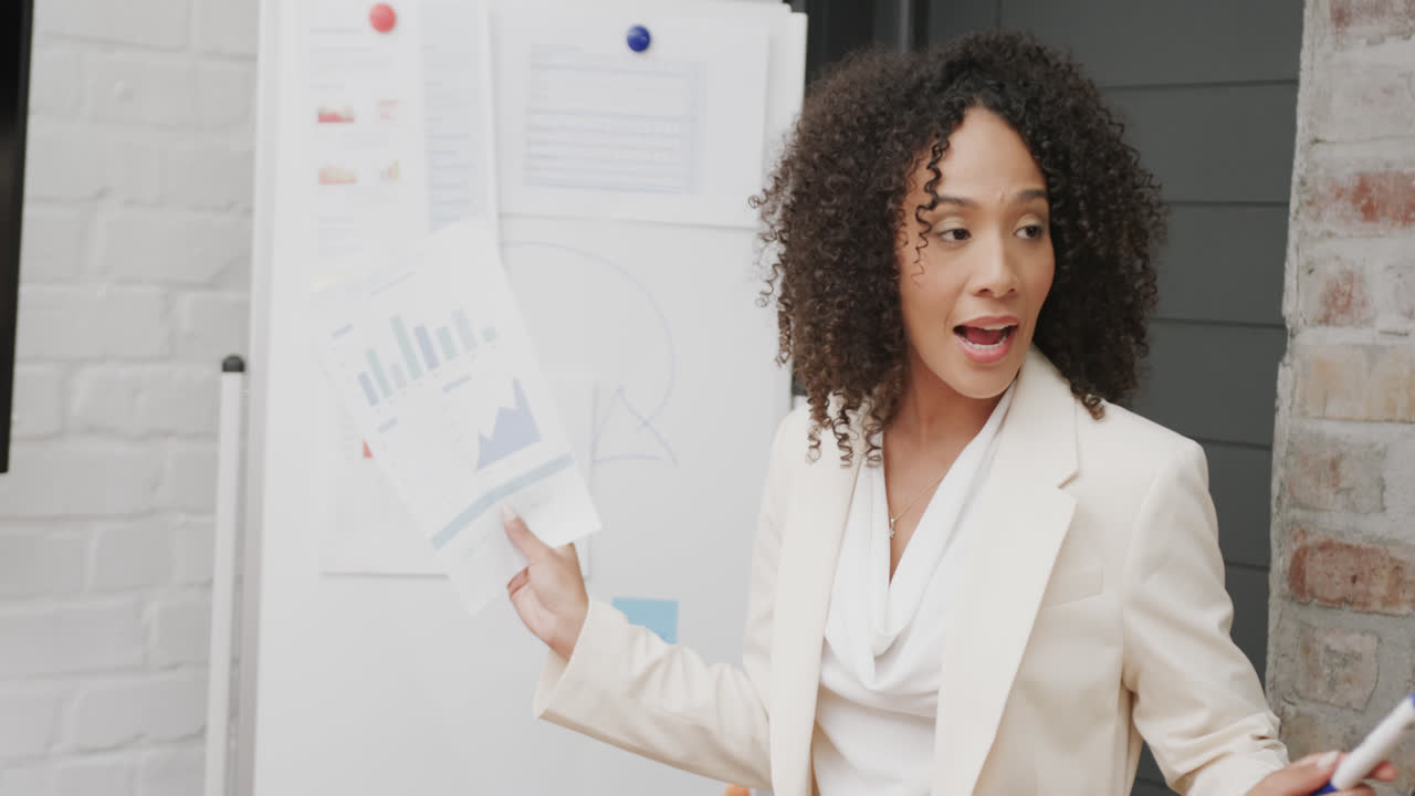 Biracial businesswoman holding document and talking at office meeting, in slow motion