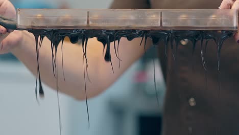 confectioner in black uniform punches chocolate out of form