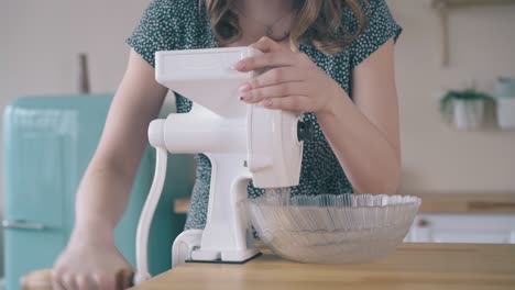 Mädchen-Dreht-Den-Griff-Einer-Mühle,-Um-Bio-Lebensmittel-Am-Tisch-Zu-Kochen