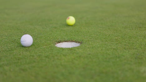 golf balls on the green near the hole
