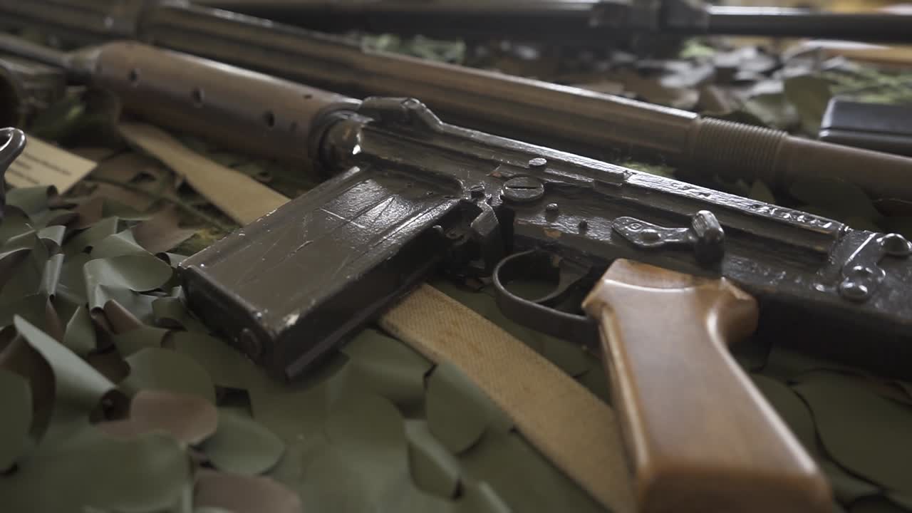 Heckler and koch g3 battle rifle resting on green camouflage surface, showcasing detailed metallic and wooden textural elements of classic military weapon