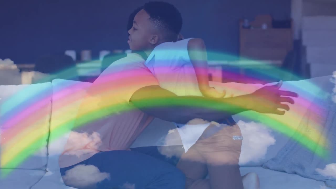 animación de arco iris sobre feliz padre y hijo afroamericanos abrazándose en el sofá
