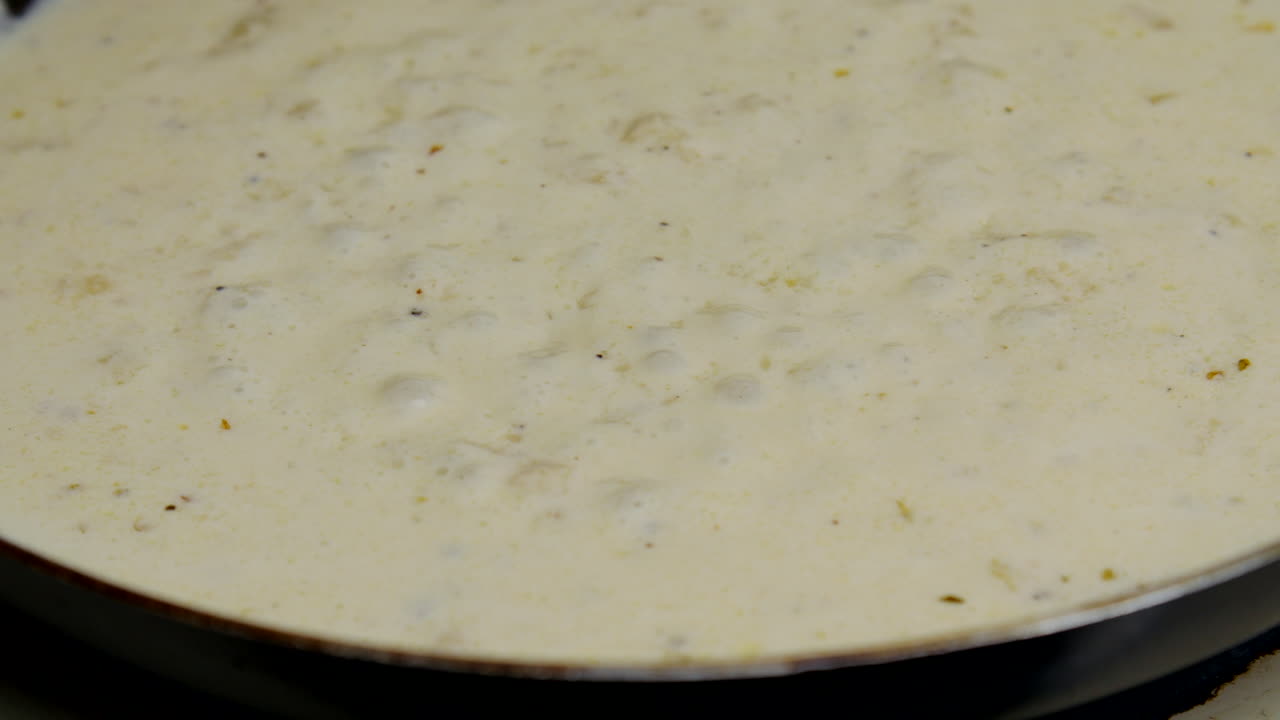Alfredo sauce simmers on the stove top