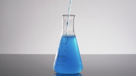 video of glass laboratory beaker with blue liquid with copy space on white background