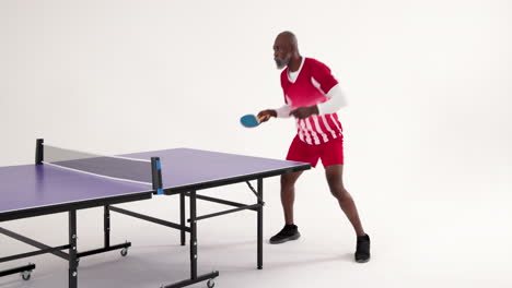 playing table tennis, african american man in red sportswear focusing on hitting ball