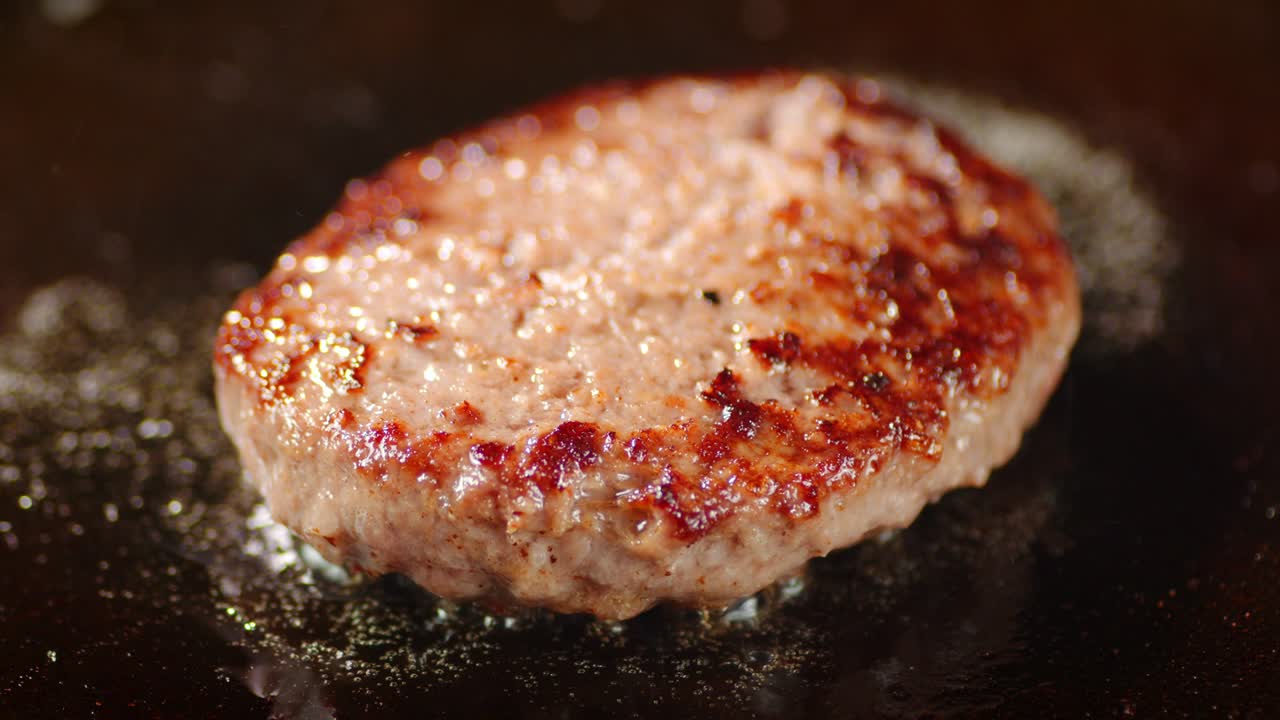 김판에 기름 거품과 함께 긴 햄버거 고기.