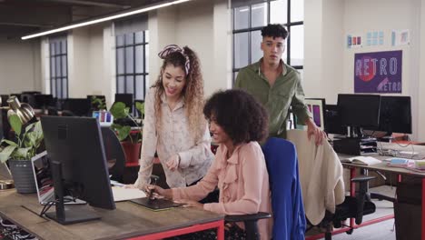 Two-happy-diverse-female-creative-designers-in-discussion-at-computer-in-casual-office,-slow-motion