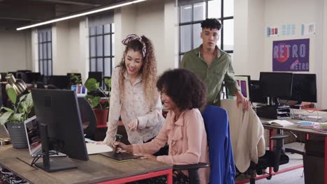 dos felices diseñadoras creativas diversas en discusión en la computadora en una oficina casual, cámara lenta