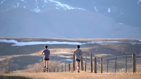 two men running on a dirt road in countryside