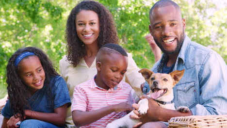 una joven familia negra sentada con un perro mascota en el jardín