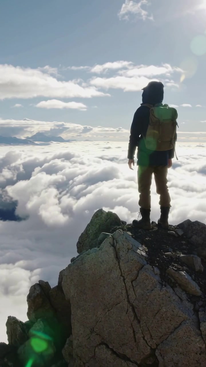 Video verticale: Escursionista di fronte che si gira mentre il sole sorge sulla cima per guardare l'alba, con la giacca e spazio per il testo.