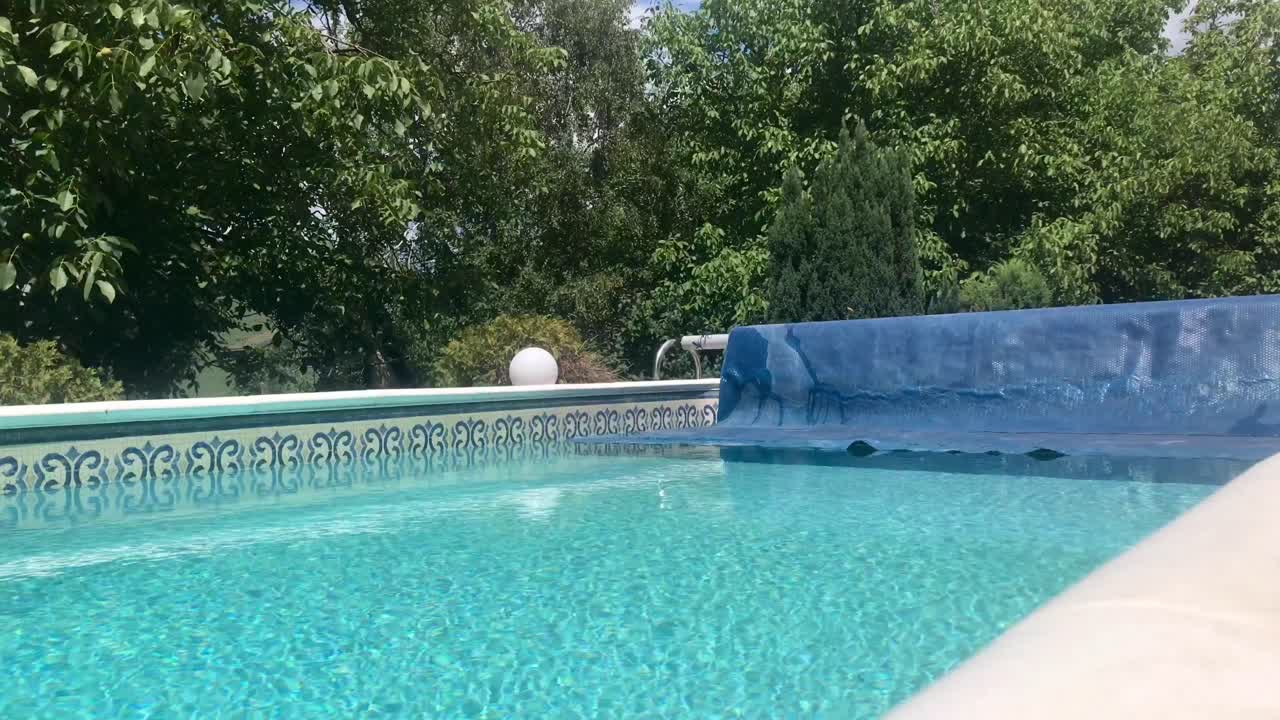 enrollando la manta del carrete de la cubierta solar y revelando una piscina limpia con fondo verde