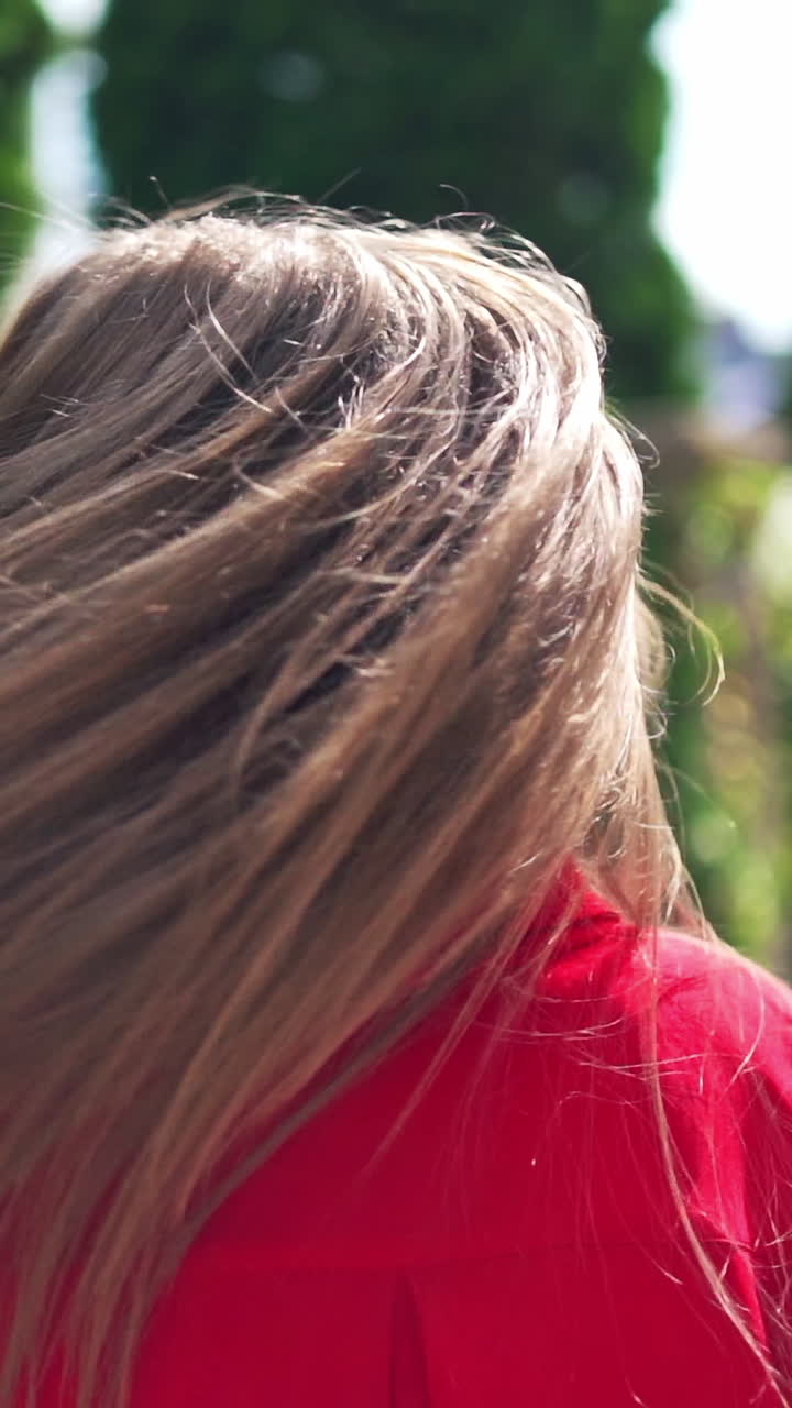 Portrait of attractive young female in summer. Beautiful woman with long hair turning around herself happily. Pretty woman walking along the street. Vertical video