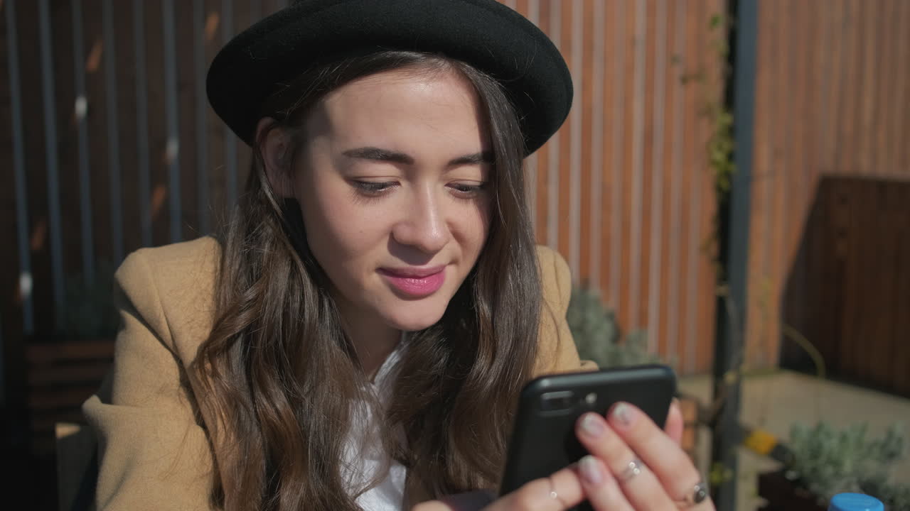 donna che usa uno smartphone in un caffè all'aperto