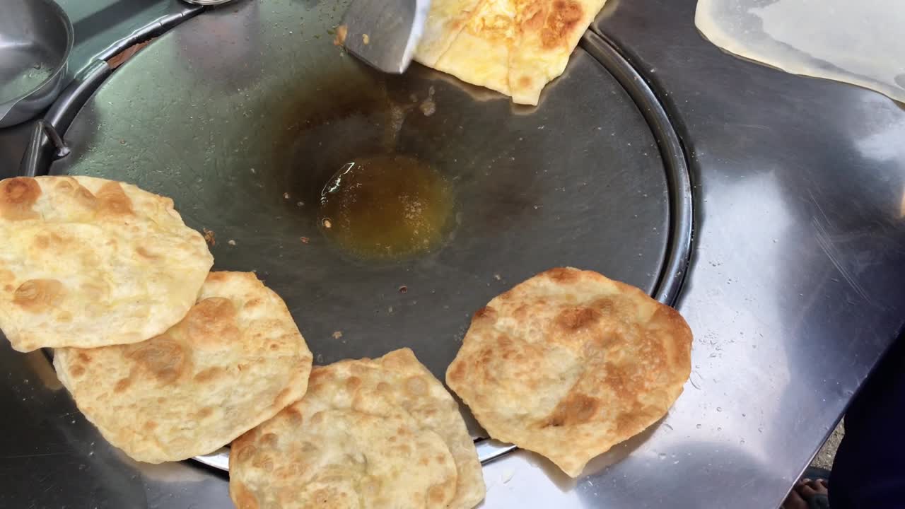 cocinar panqueques tailandeses exóticos, roti malaysian con diferentes rellenos en un mercado de tailandia. hacer rollo de roti de huevos en sartenes de metal calientes con aceite hervido. comida callejera de tailàndia. postre tailandés.