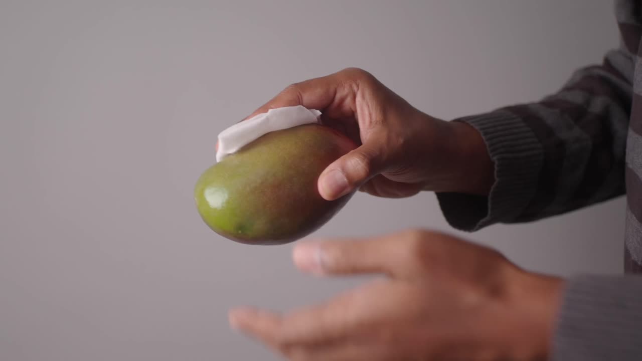 Persona limpiando un mango fresco con un paño