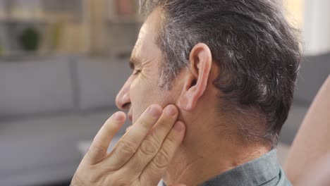 Mature-man-with-sore-ears-rubbing-his-ear-with-hands.