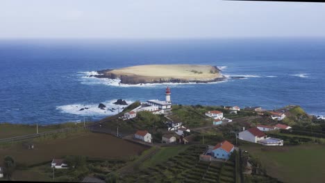 drone view push in on a lighthouse and an island in the atlantic ocean, cloudy sky in topo, são jorge island, the azores, portugal