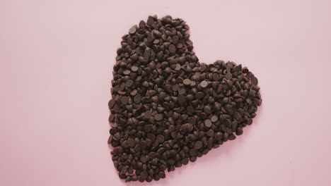 video of heart formed with chocolate chip and copy space over pink background