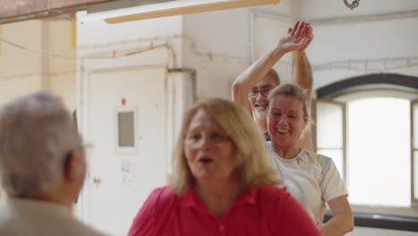 medium shot of happy senior couple dancing waltz in dance studio