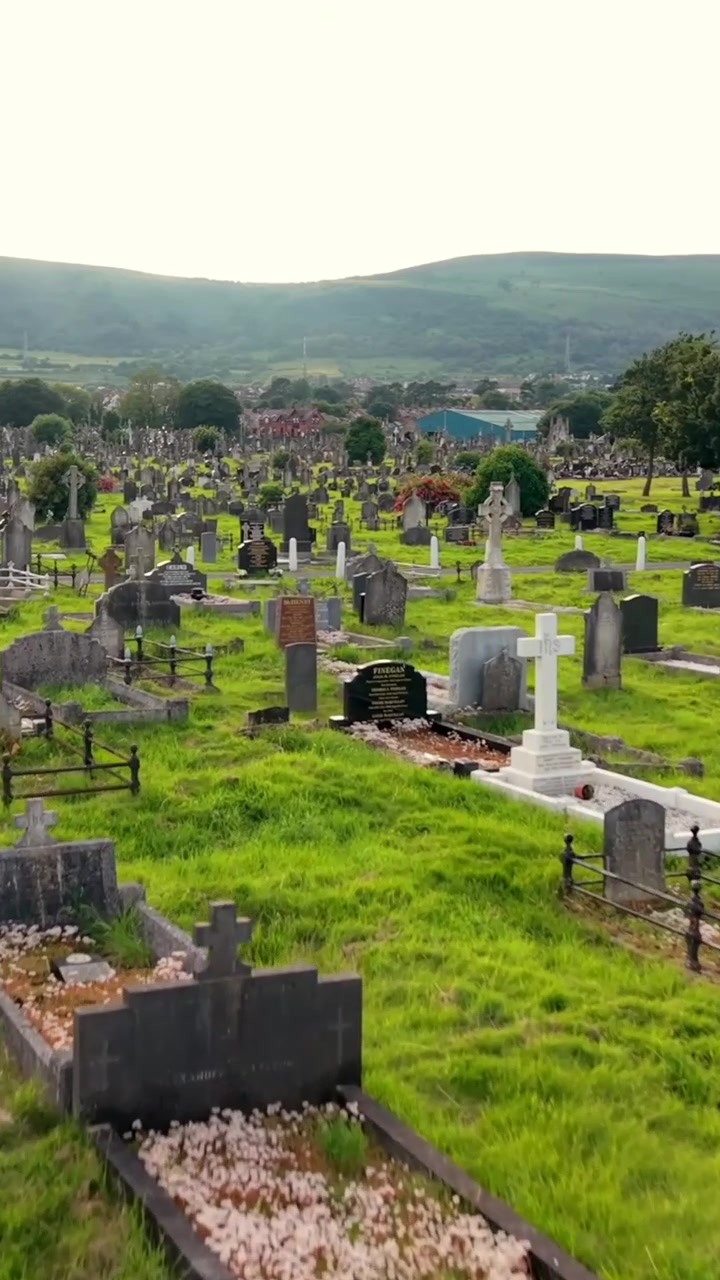 Video aereo verticale a 60FPS per social media del cimitero di Milltown e del Republican Plot a West Belfast, Irlanda del Nord, nel Regno Unito, in una giornata di sole splendente. Prodotto con colorazione Rec709.
