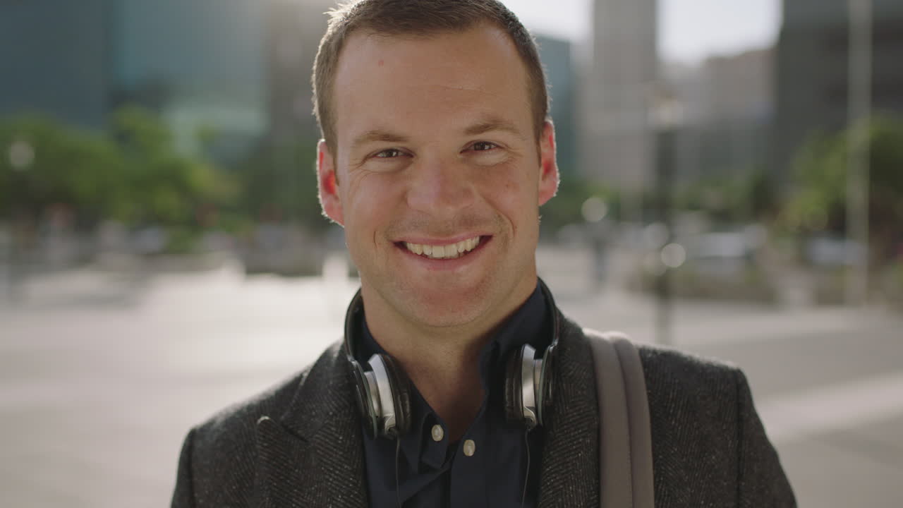 close up portrait of successful young caucasian businessman executive smiling happy at camera looking confident in urban city background