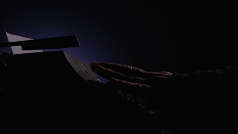 Close-up-side-view-of-hands-typing-on-a-vintage-typewriter-in-a-dark-room