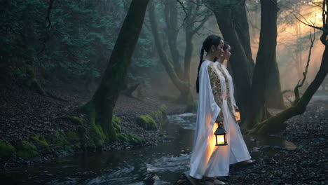dos mujeres caminando a través de un bosque místico con linternas