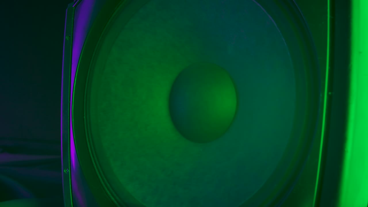 altavoces de audio membranas que reproducen música moderna produciendo un fuerte sonido de subwoofer. coloreado con coloridas luces de neón de discoteca. concepto de fiesta de rock o baile. up close. movimiento lento
