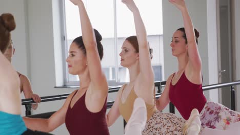 caucasian ballet female dancers exercising together with a barre by a mirror during a ballet class