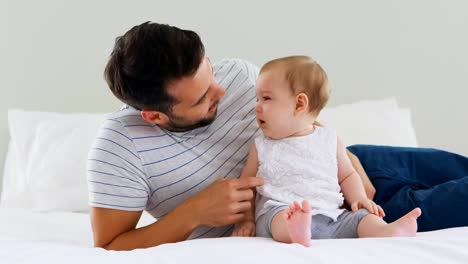 father playing with his baby girl in bedroom
