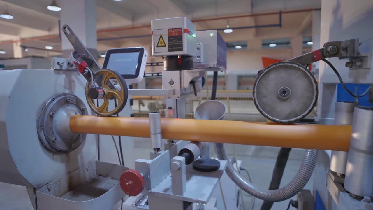 Close-up view of machinery used in the production of yellow PVC pipes in a modern industrial facility, showcasing advanced manufacturing technology.