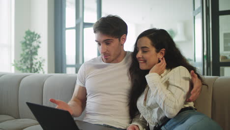 una joven pareja casada haciendo una llamada por skype en casa. una pareja feliz agitando las manos.