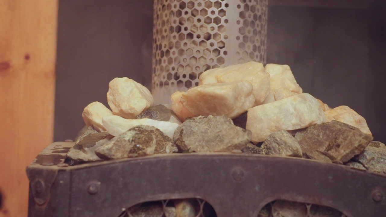 close up of hot sauna stones steaming after water poured over them from metal ladle, wooden panels glowing with heat, capturing moment of serene spa ritual