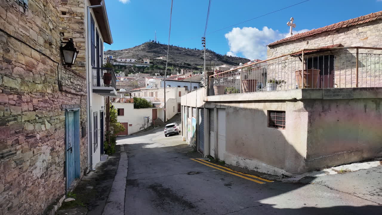 calle estrecha en lefkara con casas de piedra y una colina en el fondo