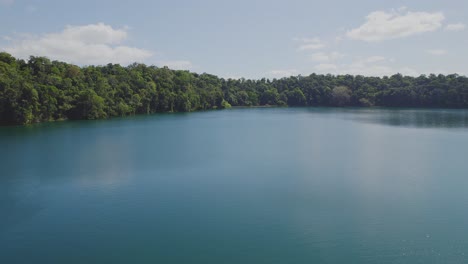 Lago-Eacham---Lago-Azul-Rodeado-De-Exuberante-Selva-Tropical-En-Atherton-Tableland,-Queensland,-Australia---Toma-Aérea-De-Drones