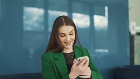 Una-Bella-Mujer-Vestida-Profesional-Recibe-Un-Mensaje-Alegre-En-Su-Teléfono-Inteligente-Y-Sonríe-En-Respuesta