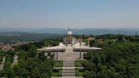 Braga-Sameiro-sanctuary-amid-forested-hills,-aerial-fly-out-reveal