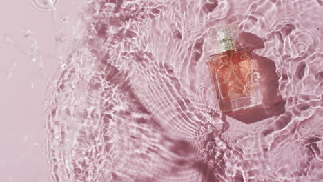 video of beauty product bottle in water with copy space on pink background