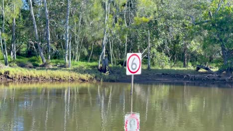 calm river scene with speed limit sign