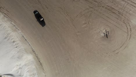 top down view of the beach and dunes, turning left and following a truck driving on the beach