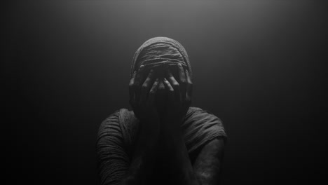 a mummified woman against the dark background in keeps her hands on her face the powerful pose full of despair