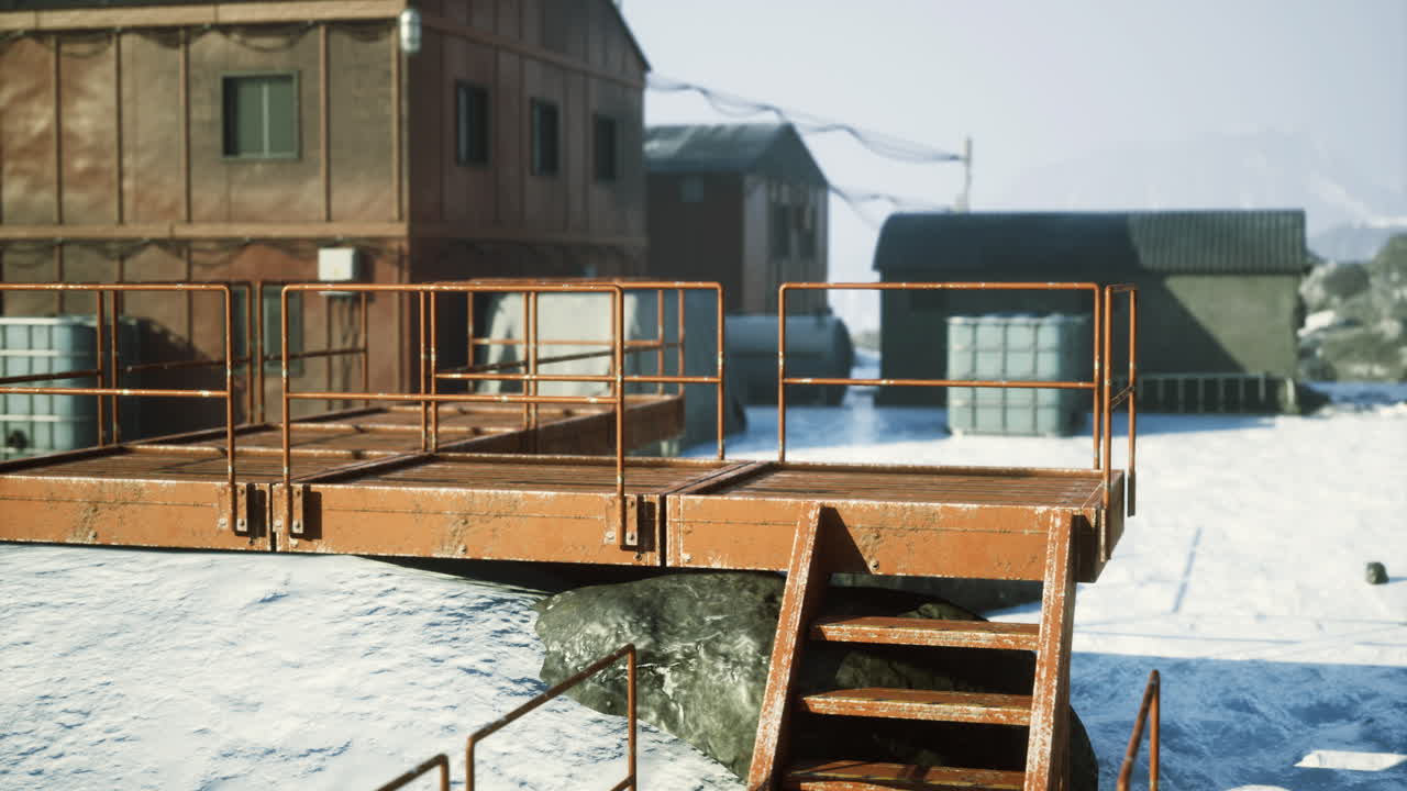 Rusty stairs lead to storage buildings in a snowy landscape during winter