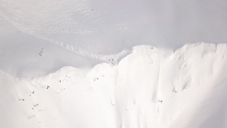 top view of a snowy mountain peak with moving human figures