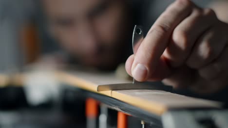 luthier comprueba el radio del fretboard de la guitarra eléctrica después de lijar, reparación de los instrumentos musicales en el taller de guitarra, 4k 60p 10 bits