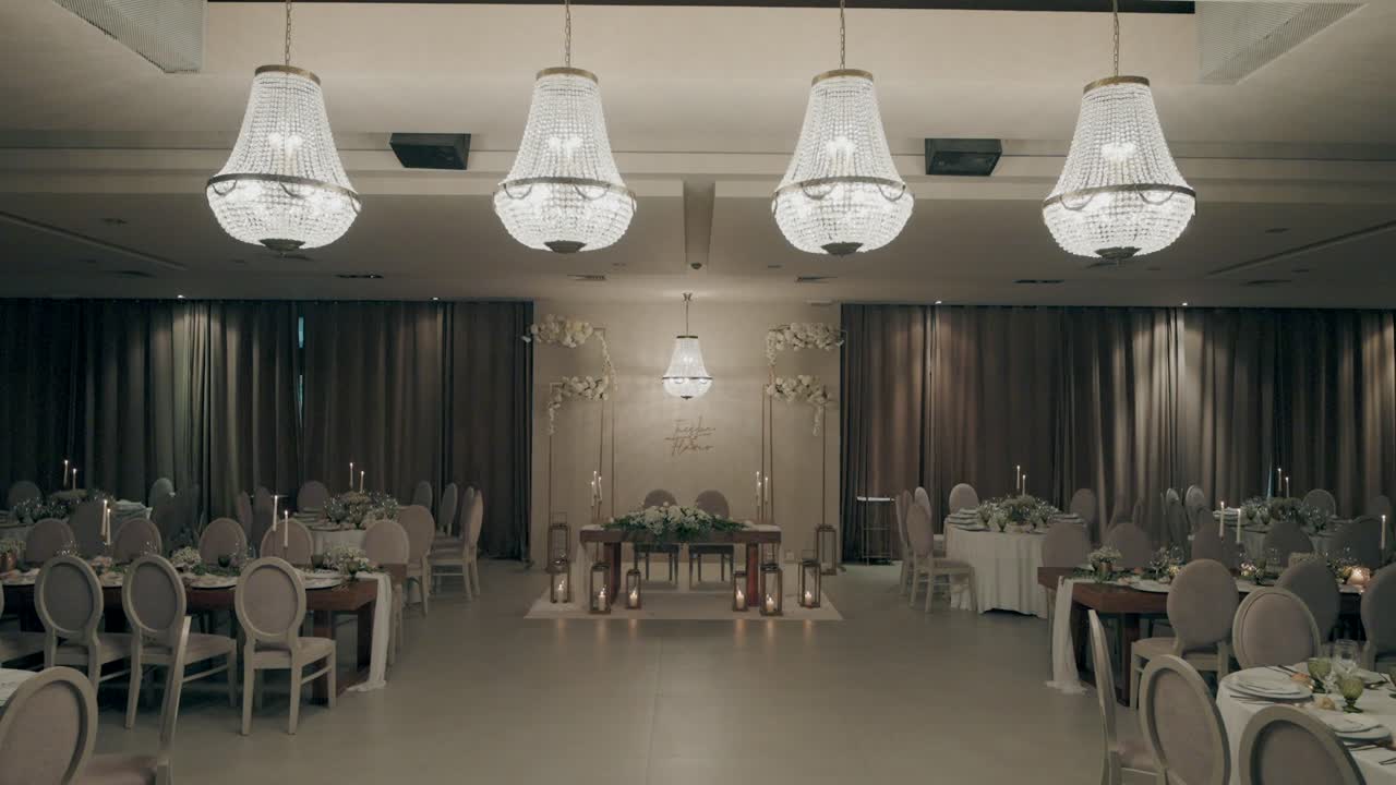 Elegant dining hall with chandeliers, softly lit and ready for an event