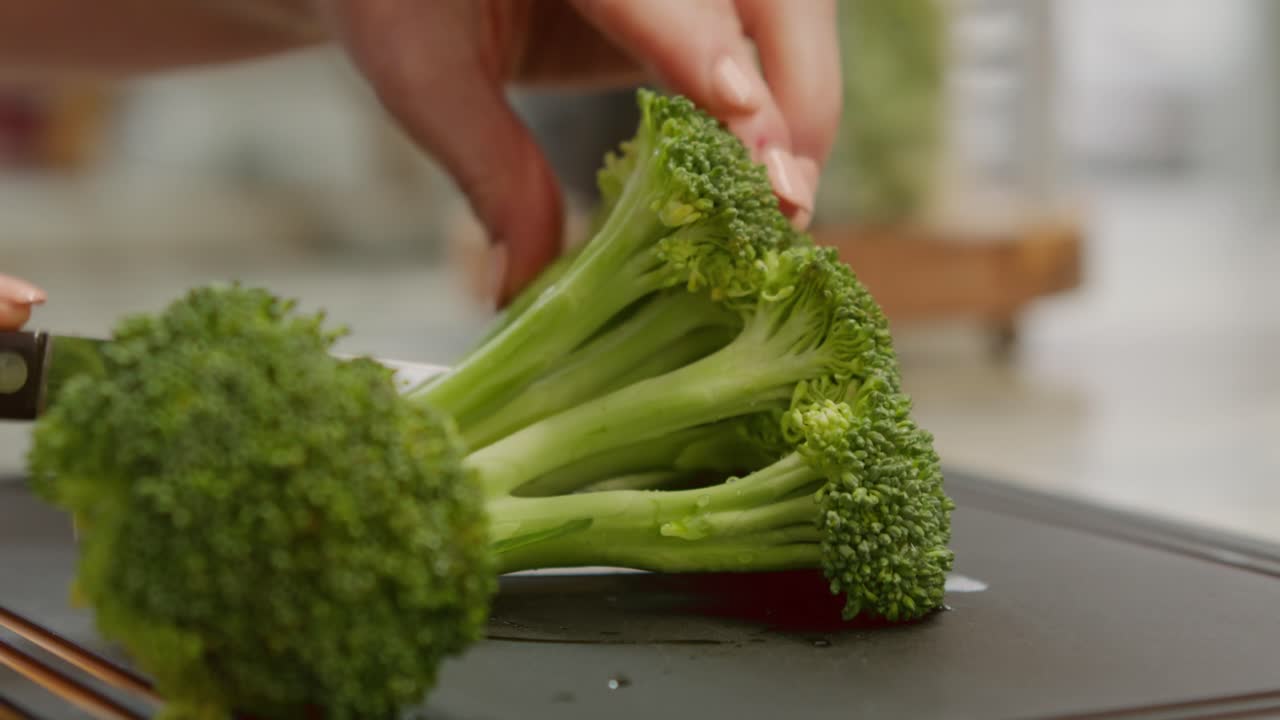 Close-up of broccoli being prepared and slices on a cutting board