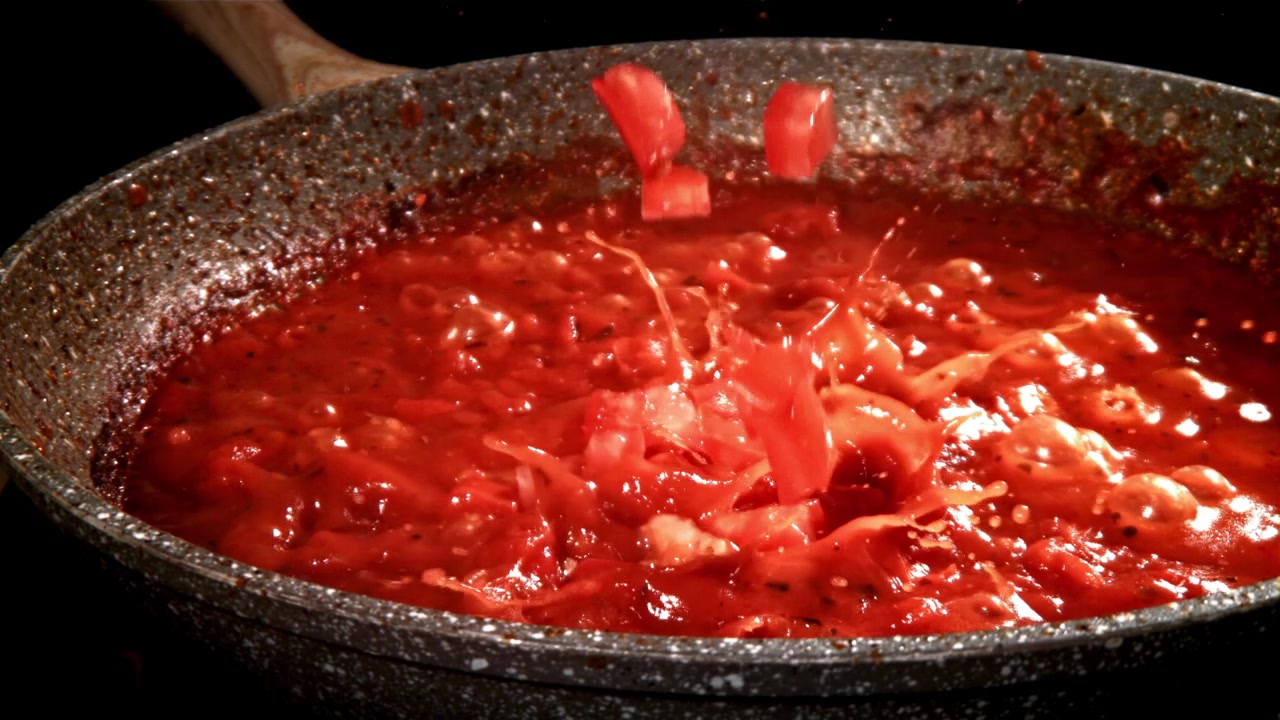 Câmera Lenta de Tomates Picados Espirrando em Molho de Tomate Quente