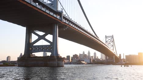 the philadelphia skyline captured at sunset framed by the benjamin franklin bridge, captured from the camden waterfront